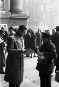Italia Dopoguerra. Milano - galleria Vittorio Emanuele - Un venditore ambulante di giornali con un cliente