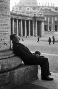Roma. Scorcio di Piazza San Pietro. In primo piano un uomo anziano si riposa seduto ai piedi di una colonna