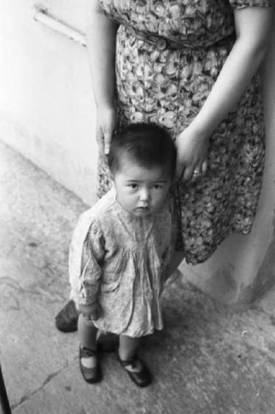 Italia Dopoguerra. Milano - Quartiere cinese - bambina cinese con una figura femminile alle sue spalle