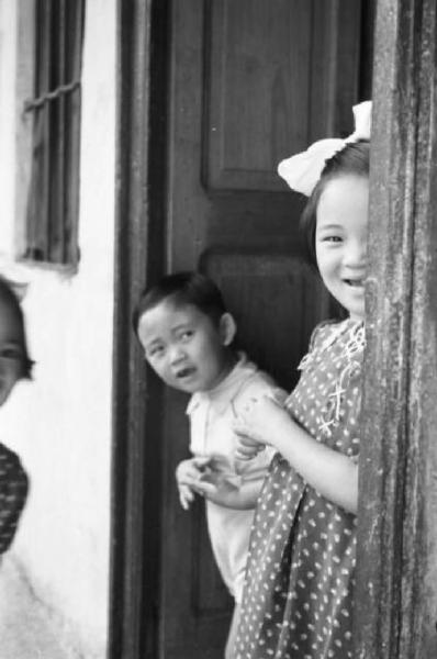 Italia Dopoguerra. Milano - Quartiere cinese - alcuni bambini sorridenti sulla soglia della loro abitazione