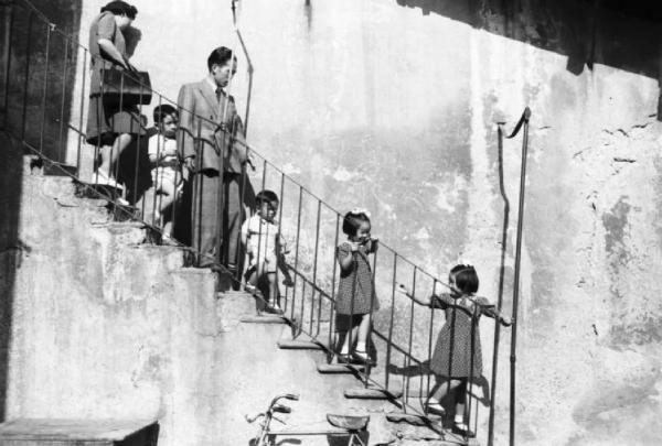 Italia Dopoguerra. Milano - Quartiere cinese - gruppo di bambini scende le scale insieme a coppia di adulti