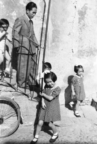 Italia Dopoguerra. Milano - Quartiere cinese - gruppo di bambini scende le scale con un uomo adulto