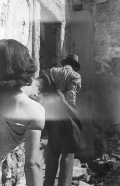 Italia Dopoguerra. Milano - Una donna di spalle semisvestita si sporge per osservare un uomo che si allontana infilandosi la giacca