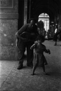 Roma - Scorcio di un porticato sotto il quale un uomo suona la chitarra mentre una bimba balla