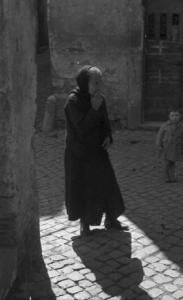 Castel Gandolfo. Scene di vita quotidiana - una donna anziana cammina per strada, alle sue spalle un bambino