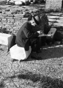 Roma. Fori Imperiali. Uomo anziano seduto tra le rovine legge un giornale