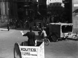 Italia Dopoguerra. Milano - Piazza del Duomo - vigile dirige il traffico da una pedana che riporta indicazioni stradali