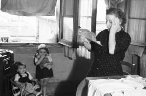 Italia Dopoguerra. Milano - Scene di vita famigliare - una donna legge una lettera con espressione preoccupata mentre due bambine sullo sfondo la osservano