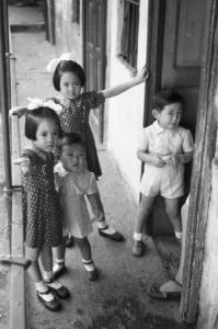Italia Dopoguerra. Milano - Quartiere cinese - gruppo di bambini sul ballatoio di una casa a ringhiera davanti alla soglia della loro abitazione