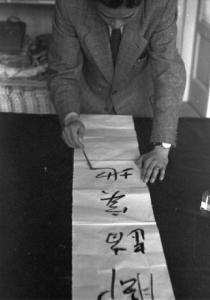 Italia Dopoguerra. Milano - Quartiere cinese - un uomo cinese traccia ideogrammi su un foglio di carta