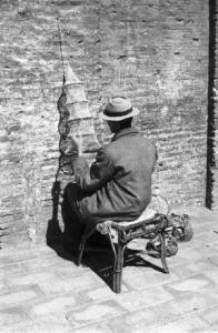 Roma. Un uomo seduto per strada ripara un retino da pesca