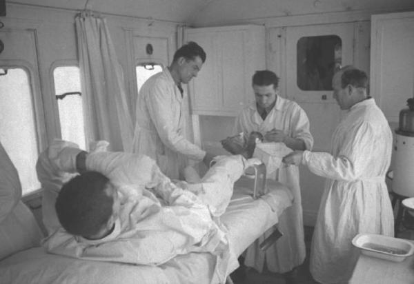 Campagna di Russia. Treno ospedale - sala medicazioni - medici eseguono una medicazione al piede congelato di un paziente - militare