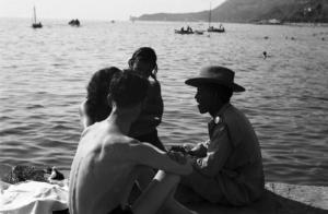 Italia Dopoguerra. Trieste. Un militare di colore conversa con alcuni triestini in riva al mare