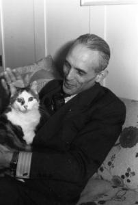 Ritratto maschile - un uomo seduto in soggiorno tiene tra le mani un gatto - Johnny Delagrange (?)