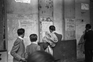 Italia Dopoguerra. Genova - Gruppo di uomini legge pagine di quotidiani affisse su un muro