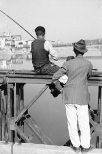 Italia Dopoguerra. Firenze - Pescatori seduti sul parapetto del Victory Bridge