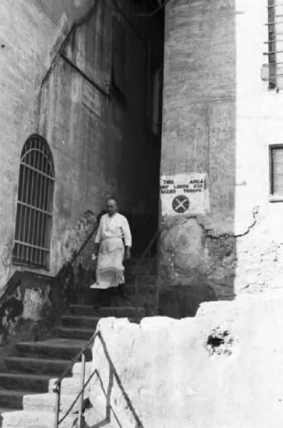 Italia Dopoguerra. Genova - Uomo in grembiule scende una scalinata - cartello in lingua inglese che definisce l'area "off limits"