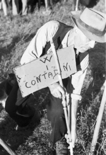 Invasione delle terre. Un anziano contadino pianta un cartello con la scritta "W i contadini"