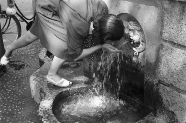Milano. Parco Sempione. Una donna beve dalla "Fontana dell'acqua marcia"