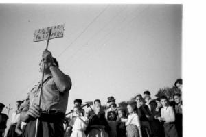 Invasione delle terre. Gruppo di contadini che manifestano. Un uomo solleva un cartello con scritto "la terra a chi la lavora":