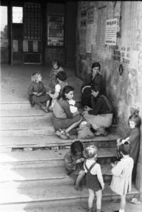 Italia Dopoguerra. Genova - Alcune donne siedono con i loro bambini sui gradini di un edificio