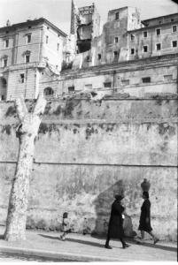 Italia Dopoguerra. Terracina. Scorcio del paese. Due donne e una bambina caminano lungo un viale, una trasporta una brocca
