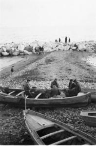 Italia Dopoguerra. Napoli. Pescatori sgarbugliano le reti seduti su barche tirate in secca su una spiaggia