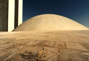 Brasilia. Bicicletta da corsa davanti a una delle due cupole del Congresso Nazionale, con la base del doppio grattacielo sullo sfondo