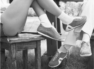Atalasport. Gambe di una coppia che calza scarpe Atala si incrociano sotto un tavolo all'aperto
