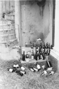 Bottiglie abbandonate in un cortile, ai piedi di una scala