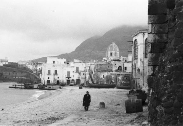 Italia Dopoguerra. Forio. Il paese. Un uomo cammina lungo la spiaggia