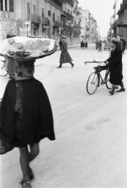 Italia Dopoguerra. Palermo. Un ragazzo con un cesto sulla testa porta del pane per le vie della città