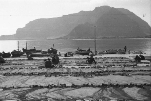 Italia Dopoguerra. Mondello. I pescatori sistemano le reti. Barche ormeggiate