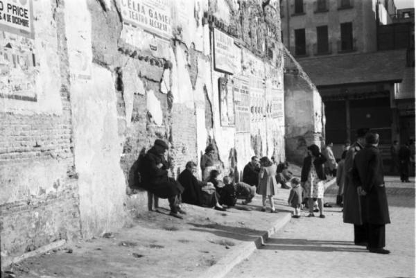 Spagna. Madrid. Vecchi e bambini seduti a ridosso di un muro in una zona disastrata della città