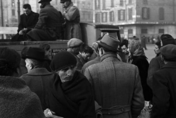 Italia Dopoguerra. Milano. Persone in attesa di salire su un camion con la scritta "Ufficio Trasporti"