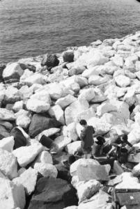 Italia Dopoguerra. Napoli. Ragazzini rovistano in bidoni di metallo abbandonati sui massi frangiflutti
