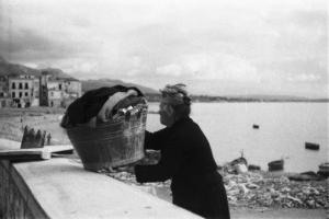 Italia Dopoguerra. Formia. Una donna anziana con un cesto di biancheria si reca verso il mare