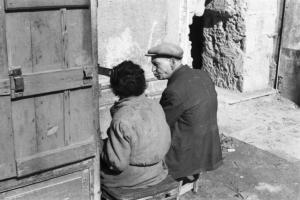 Italia Dopoguerra. Napoli. Due anziani seduti su sgabelli e di spalle