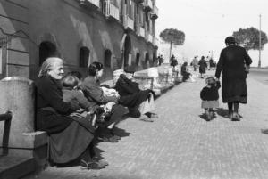 Italia Dopoguerra. Napoli. Donne con bambini guardano i passanti passeggiare