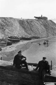 Italia Dopoguerra. Pozzuoli. Due uomini seduti su un muretto durante una pausa nei pressi del porto