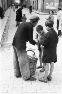 Italia Dopoguerra. Palermo. Due bambini acquistano dolciumi da un venditore ambulante