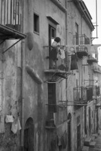 Italia Dopoguerra. Facciata di un edificio abitativo. Donna stende i panni al balcone