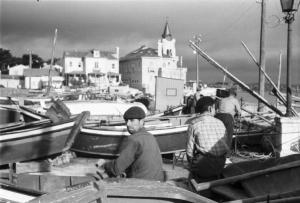 Portogallo. Cascais. Pescatori seduti sulle barca in secca - sullo sfondo gli edifici del paese