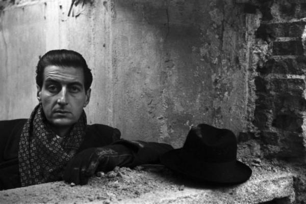 Italia Dopoguerra. Ritratto maschile, il pittore e architetto Fabrizio Clericisi posa tra le rovine di un palazzo bombardato