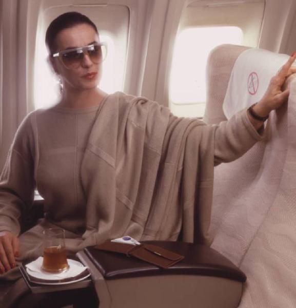 Campagna pubblicitaria Alitalia. Interno di aeromobile - business class - passeggera con tazza di tè e portafoglio