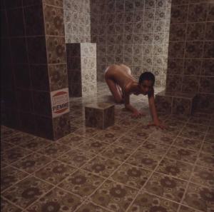 Ceramiche artistiche Piemme. Nudo femminile  posa all'interno di un bagno - in primo piano una piastrella con il marchio dell'azienda