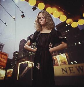 Fotomodella in abito scuro posa davanti a un fondale che riproduce una immagine della città di New York