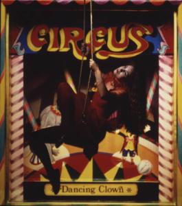 Fotomodella in abito rosso posa su altalena - sullo sfondo una locandina di circo