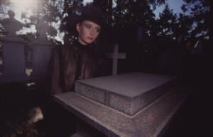 Donna (vedova) in abito seducente all'interno di un cimitero nei pressi di una tomba al cimitero Monumentale