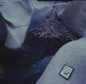 Val Verzasca - fotomodella nuda sdraiata all'interno di una conca ghiaiosa. In primo piano una riproduzione del viso di Marilyn Monroe